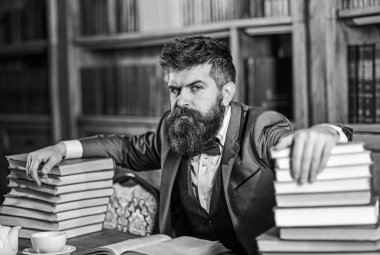 Adam masada çok kitap ile oturuyor..