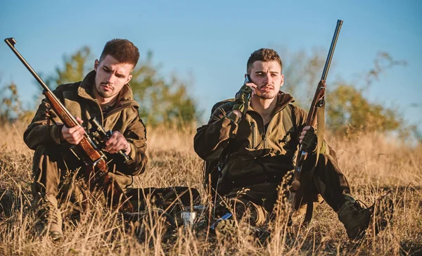 Hunters friends enjoy leisure. Rest for real men concept. Hunters with rifles relaxing in nature environment. Hunting with friends hobby leisure. Hunters satisfied with catch drink warming beverage — Stock Photo, Image