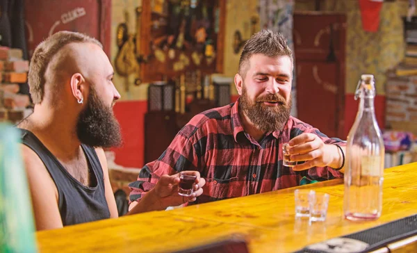 Friends relaxing in pub. Men drinking alcohol together. Alcohol addiction. Hipster brutal man drinking alcohol with friend at bar counter. Men drunk relaxing at pub having fun. Strong alcohol drinks