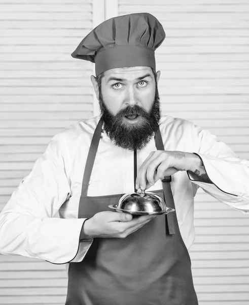 Gissa vad jag kokade. Vad som finns under locket. Läcker måltid presentation. Haute cuisine kännetecknas noggranna förberedelser och noggrann presentation måltid. Mannen hatt och förkläde hålla måltid täckt med lock — Stockfoto