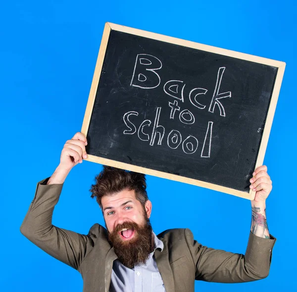 Maradj pozitív. Tanár szakállas férfi birtokolja tábla felirattal vissza az iskolába kék háttér. Tanár kócos haja vidám a tanév elején. Eltartás működő és lenni fajta-hoz emberek — Stock Fotó