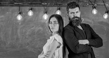 Sakallı adam ve gözlüklü öğretmen arka arkaya, arka planda tebeşir tahtası. Öğretmen ve öğretmen kendinden emin görünüyor. Okul personeli kavramı. Lady ve hipster schoo birlikte çalışıyor