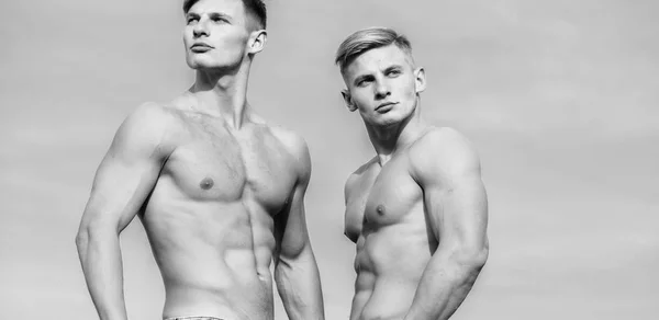 Men twins brothers muscular guys sky background. Men strong muscular athlete bodybuilder. Attractive muscular twins. Muscular healthy athletic body. Sexy torso attractive body. Masculinity concept