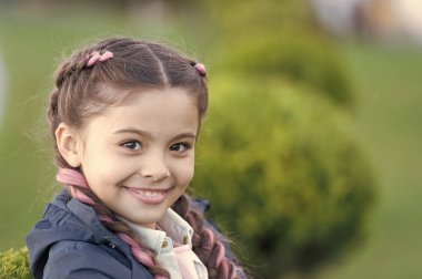 Parlak detay ekle. Şirin örgü ören küçük bir kız doğayı yakından takip ediyor. Kanekalon, şirin çocuk örgüleri içinde. Modern saç modeli konsepti. Pembe kanekalonlu örgülü saçlı kız.