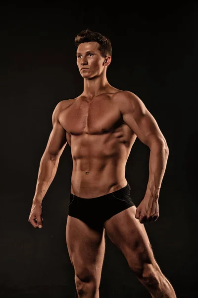 Maço kas vücut poz vücut geliştiricisi, siyah arka plan ile. Siyah iç çamaşırı vücut kasları gösterir. Atlet emin yüz kas vücut gösterir. Vücut geliştirme kavramı — Stok fotoğraf
