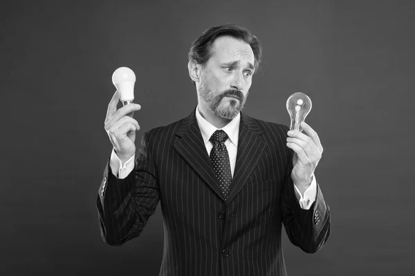 Symbol of idea progress and innovation. Idea for business. Environment friendly idea. Genius idea. Light up your business. Man bearded businessman formal suit hold light bulb on red background