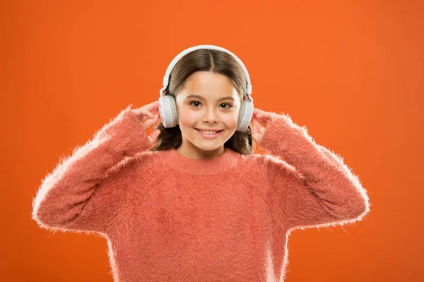 ส่งเสียงไปทางหูของเธอด้วยหูฟัง เด็กเล็กฟังเพลงในหูฟังไร้สาย สาวน้อยสวมหูฟังสมัยใหม่ เด็กน่ารักเพลิดเพลินกับเสียงสเตอริโอในหูฟัง — ภาพถ่ายสต็อก