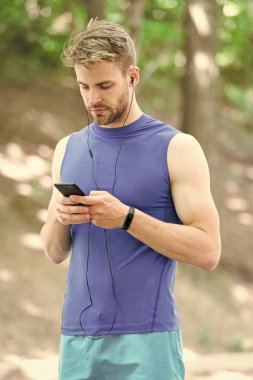 Adam atlet meşgul yüz kadar çalma listesi, Doğa arka plan ayarlayın. Adım sayar ve kulaklık becerikli alet eğitim sporcu. Atlet ile kıl fitness izci veya adım sayar. Gadget'ı yapmak hayat daha kolay