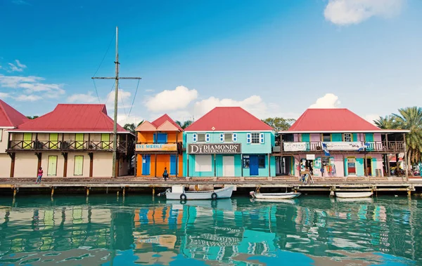 圣约翰, 安提瓜-2016年3月05日: 船停靠在海边的村庄码头, 在蓝天上的房子。热带岛的暑假。发现和冒险。流浪 — 图库照片