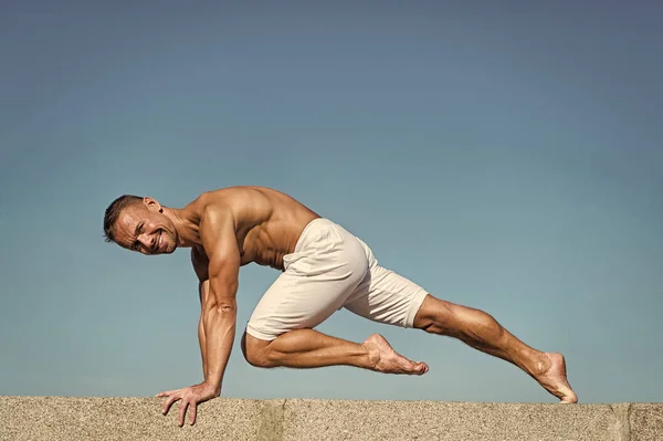 Man practicing yoga blue sky background. Reached peace of mind. Meditation and yoga concept. Yoga helps find balance. Practice asana outdoor. Yoga practice helps find harmony and balance