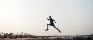 Sıkı koş ya da eve yürü. Sahilde koşan adam. Koşucu eğitim açık havada. Fit yaz aylarında erkek spor fitness egzersiz. Koşu sporu ve hobi. Günlük egzersiz büyük sonuç. Erkek profesyonel fitness antrenörü