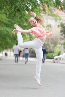 Dans ediyorum. Dans eden kız. Sevimli dansçı şehir caddesinde özgür hissediyor. Küçük çocuk modern müzik le dans etmekten hoşlanır. Enerjik küçük kız zevkle dans