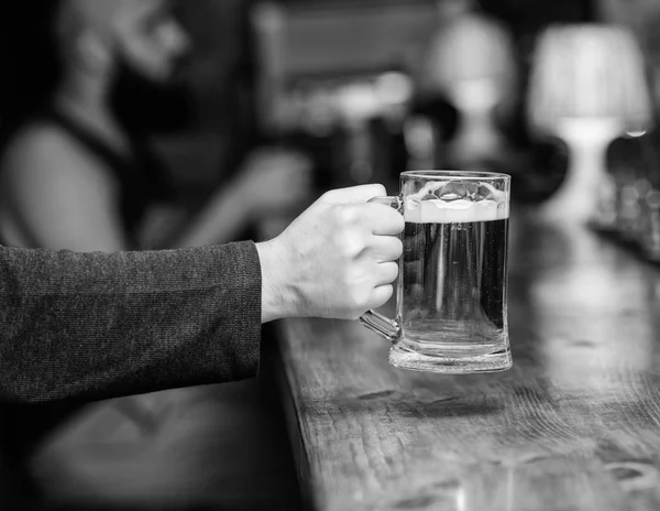 Glass with fresh lager draft beer with foam. Male hand holds mug filled with cold tasty beer in bar. Friday leisure tradition. Beer pub concept. Beer mug on bar counter defocused background — Stock Photo, Image