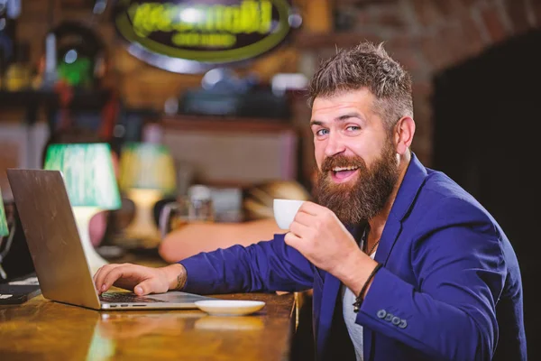 Surfing internet. Man bearded businessman sit pub with laptop and cup of coffee. Freelance benefit. Manager work online while enjoy coffee. Online job. Hipster freelancer work online blog notebook