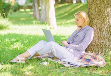 Doğal çevre ofisi. Açık havada faydaları iş. Dizüstü bilgisayar işleriyle açık havada ağaç gövdesinde yağsız olan kadın. Eğitim teknolojisi ve internet kavramı. Kız iş park dizüstü bilgisayar ile oturup çimenlerin üzerinde
