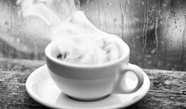 Jesienna pogoda pochmurne, lepiej z kofeiny napój. Korzystania z kawy, na deszczowy dzień. Kawy czas na deszczowy dzień. Świeże parzonej kawy w białe filiżanka lub kubek na parapecie. Mokre szybę i kubek gorącej kawy — Zdjęcie stockowe