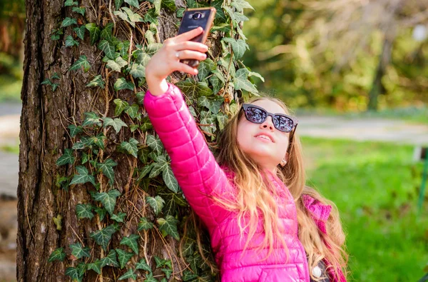 Criança feliz no parque. Hora da selfie. Beleza natural. Felicidade infantil. Natureza de verão. A menina faz selfie no parque. Férias. Ambiente verde. planta de escalada na árvore com folhas de hera — Fotografia de Stock