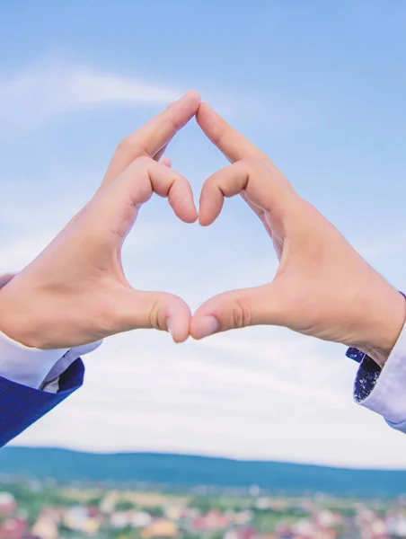 Manos masculinas en forma de corazón símbolo de gesto de amor y romance. El gesto del corazón de la mano forma usando los dedos. Manos juntas en forma de corazón fondo cielo azul. Concepto de símbolo de amor — Foto de Stock