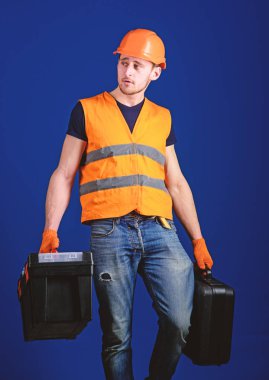 Donanımlı tamirci kavramı. İşçi, tamirci, tamirci, Oluşturucu profesyonel araçlar ile sakin yüz taşıdığı çanta üzerinde. Araç kutusu ve araç, mavi arka plan ile bavul kask, kask içinde adam tutar