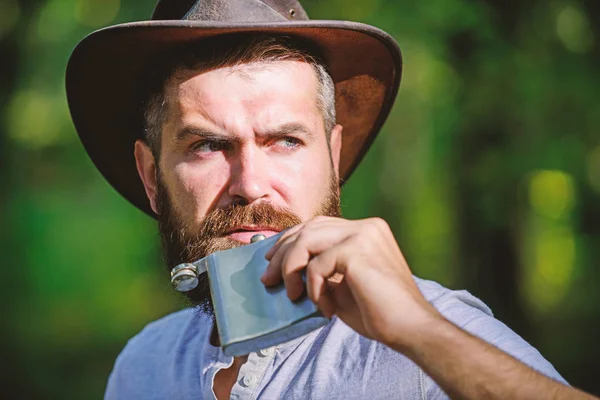 Alcohol drink. Nomadic man carry alcohol with him. Guy brutal bearded cowboy drink alcohol metal flask. Hipster with beard drink alcohol nature background defocused. Adventure begins from first sip — Stock Photo, Image