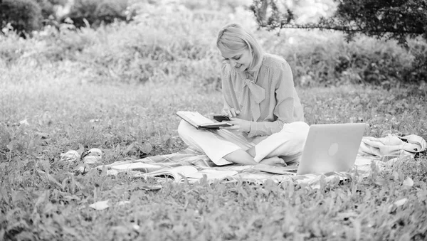 Business lady freelance work outdoors. Become successful freelancer. Woman with laptop sit on rug grass meadow. Girl with notepad write note. Freelance career concept. Guide starting freelance career