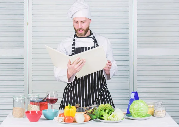 Mannen skäggig kock Matlagning mat. Guy läsa bok recept. Måltidskunskap koncept. Man lära dig recept. Förbättra matlagning skicklighet. Boka familjerecept. Ultimata matlagning guide för nybörjare. Enligt receptet — Stockfoto