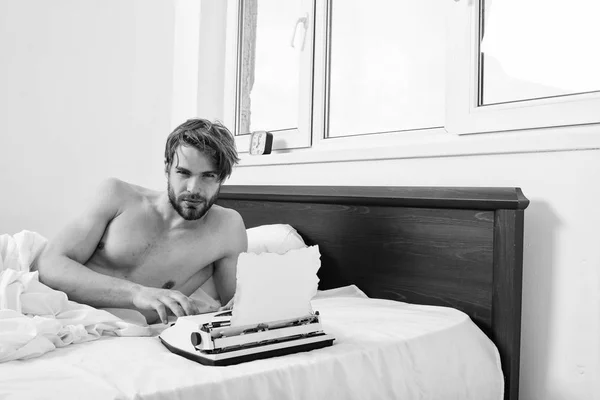 Writer author used to old fashioned machine instead of digital gadget. Man writer lay on bed white bedclothes working on new book. Morning inspiration concept. Guy create new chapter use typewriter — Stock Photo, Image
