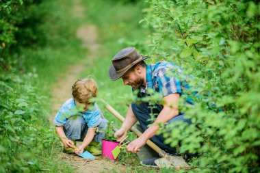 Bahçe araçları. Bahçe hobi. Babam küçük oğul bakım fabrikalarında ders veriyor. Bahar bahçe rutin. Çiçek dikmek. Bahçede küçük yardımcı. Çiftlik ailesi. Doğa arka planda küçük çocuk ve baba