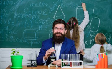 Adam sakallı öğretmen biyoloji sınıfında mikroskop ve test tüpleri ile çalışır. Biyoloji karmaşık yaşam formlarının anlaşılmasında rol oynar. Biyoloji öğretmeni. Çocuklara biyolojiyi açıklamak