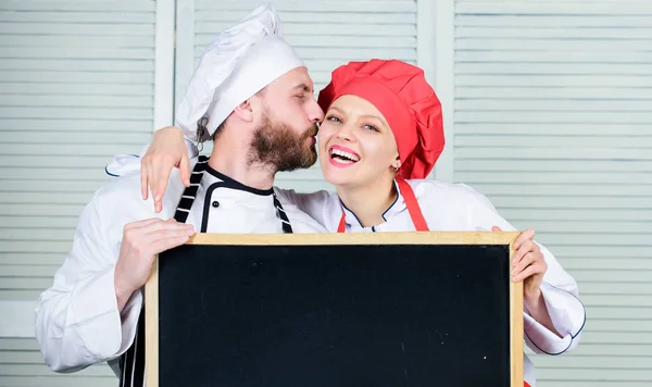 Man and woman chef cooking food together. Couple with blackboard for advertisement. Lovely family at kitchen. Family restaurant. Family day. Couple in love cooking together. Family values. Share joy