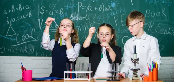 Gli alunni delle scuole di gruppo con provette studiano liquidi chimici. Concetto scientifico. Ragazze e ragazzo che forniscono esperimento con liquidi. Provette con sostanze liquide colorate. Studio degli stati liquidi — Foto Stock