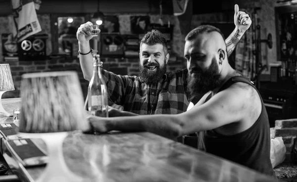 Men drinking alcohol together. Strong alcohol drinks. Alcohol addiction. Friends relaxing in pub. Men drunk relaxing at pub having fun. Hipster brutal man drinking alcohol with friend at bar counter