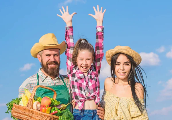 Agricultores familiares orgulhosos da colheita de outono. Conceito de festival de colheita. A vida no campo beneficia. Pais e filha agricultores estilo rústico no fundo do céu azul. Família feliz agricultores alegres jardineiros — Fotografia de Stock