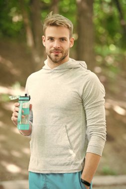Açık hava antrenmanından sonra vitamin içeceğini tazeliyorum. Adam atletik görünüşte su şişesi tutuyor. Sporcu erkek sporcu idmandan sonra şişeye su döker. Sporcu parktaki eğitimden sonra su içer