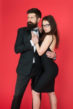 Smokinli ve zarif kız lı bir çift. Erkek sakallı hipster ve resmi elbise kırmızı arka plan lı kadın. Resmi moda ve zarif giysiler. Lüks moda butiği. Moda giyim mağazası. Resmi etkinlik