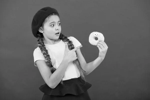 Loja de doces e conceito de padaria. Crianças enormes fãs de rosquinhas assadas. Impossível resistir ao donut feito de fresco. Menina segurar vidros bonito donut na mão fundo vermelho. Miúdo menina brincalhão pronto para comer donut — Fotografia de Stock