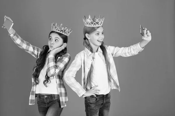 Koncepcja rozpieszczone dzieci. Księżniczka egocentryczny. Dzieci noszą złote korony symbol księżniczka. Znaki ostrzegawcze rozpieszczonego dziecka. Uniknąć, podnoszenie zepsute dzieci. Dziewczyny, biorąc selfie zdjęcie aparatu w smartfonie — Zdjęcie stockowe