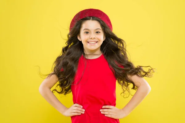 Volumen de pelo. Niña en sombrero de estilo francés. chica feliz con el pelo rizado largo en boina. infancia. peluquería. belleza de la moda de verano. niño parisino sobre fondo amarillo. concepto de volumen de cabello —  Fotos de Stock