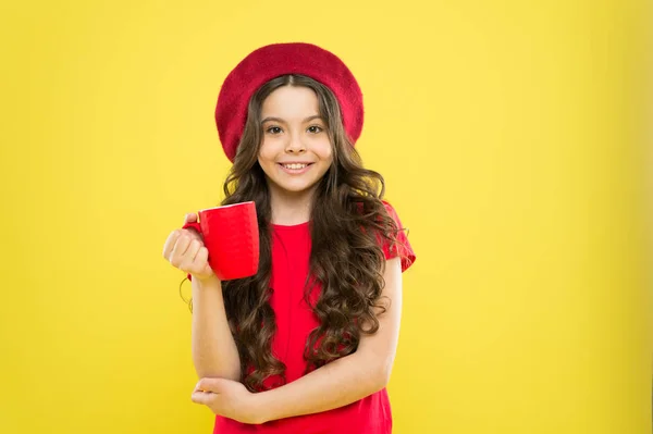 Een klein meisje met een Franse hoed. Theetijd. gelukkig meisje met lang krullend haar in baret. Schoonheidsmode. kindertijd. kapsalon. Parijse kind op gele achtergrond. Afhaalkoffie. positieve stemming — Stockfoto