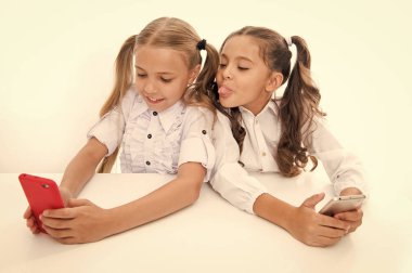 eğleniyor. mutlu küçük çocuk kızlar okulda cep telefonu ile eğleniyor. Dijital çağda öğrencilerin. küçük kızlar mobil olmuşsunuz