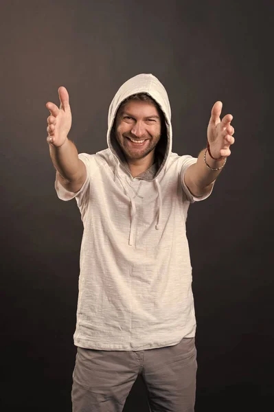 Γενειοφόρος άνδρας χαμόγελο με τεντωμένα χέρια. Ευτυχισμένος άνθρωπος με γενειάδα φορούν κουκούλα. Μόδα μοντέλο σε hoodie tshirt. Ενεργό τρόπο ζωής και την υγεία δραστηριότητα. Έννοια στυλ και η τάση της μόδας — Φωτογραφία Αρχείου