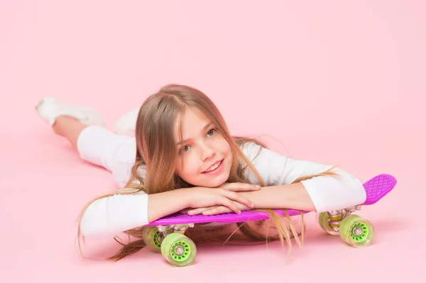 Ragazza alla moda. Alla ragazza piace andare sullo skateboard. Stile di vita attivo. Ragazza divertirsi con penny board sfondo rosa. Bambino adorabile capelli lunghi adorano cavalcare penny board. Cavalcare penny board e fare trucchi — Foto Stock