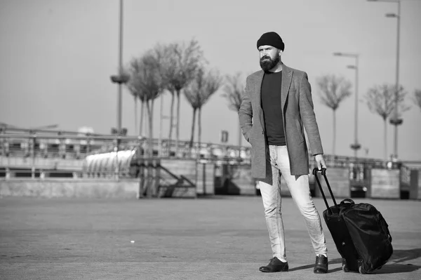 Hipster ready enjoy travel. Carry travel bag. Business trip. Man bearded hipster travel with big luggage bag on wheels. Let travel begin. Traveler with suitcase arrive to airport railway station