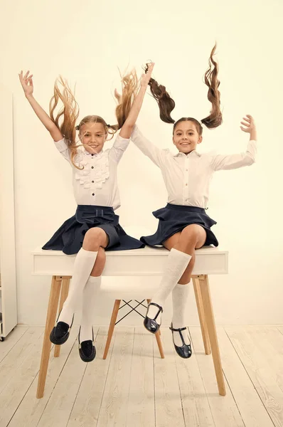 Schoolreisconcept. Schoolmeisjes leuke pony staarten kapsel zitten op het bureau. Beste vrienden vrij hebben plezier spelen met haar. Perfecte schoolmeisjes met mooi haar. School kapsels paardenstaarten in de lucht — Stockfoto