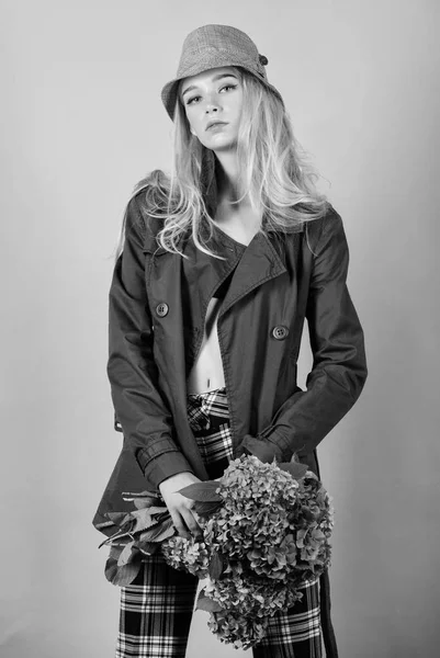 Abbigliamento e accessori. Donna capelli biondi posa cappotto con mazzo di fiori. Cappotto alla moda. Ragazza modello di moda indossare cappotto per la primavera e l'autunno stagione. Trench tendenza moda cappotto. Deve avere concetto — Foto Stock