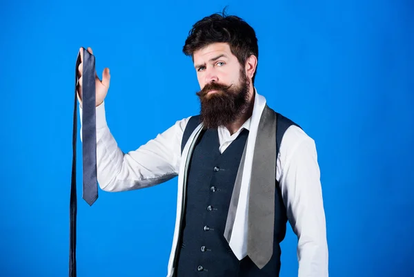 For formal occasions choose solid colored tie that is darker than your shirt. Match colors. Man bearded hipster hold few neckties on blue background. Guy with beard choosing necktie. Perfect necktie