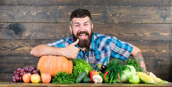 Welcome to my farm. Farmer with homegrown vegetables. Vegetables organic harvest. Farmer rustic style guy. Natural foods. Vegetarian lifestyle concept. Man bearded farmer harvest wooden background