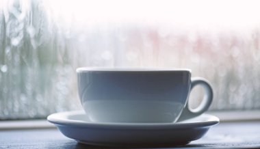 Yağmurlu bir gün kahve zamanında. Islak cam pencere ve sıcak kahve. Sonbahar bulutlu hava kafein içecek ile daha iyi. Kahve yağmurlu günde zevk. Beyaz fincan veya kupa pencere üzerinde taze yapılmış kahve