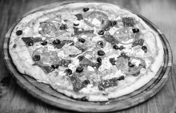 Pizza mit Dill. leckere heiße Pizza auf Holzteller. Essenslieferservice. Pizza mit Tomaten, schwarzen Oliven und Schinken Essen zum Mitnehmen. Pizzeria-Restaurant. italienisches Pizza-Konzept — Stockfoto