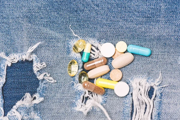 Dipendenza da droga. Medicina e concetto di trattamento. Droga su sfondo denim. Set di pillole colorate. Miscelazione di medicinali. Trattamento veloce. Prescrizione di medicinali. Assistenza sanitaria e malattia. Dose e dipendenza — Foto Stock